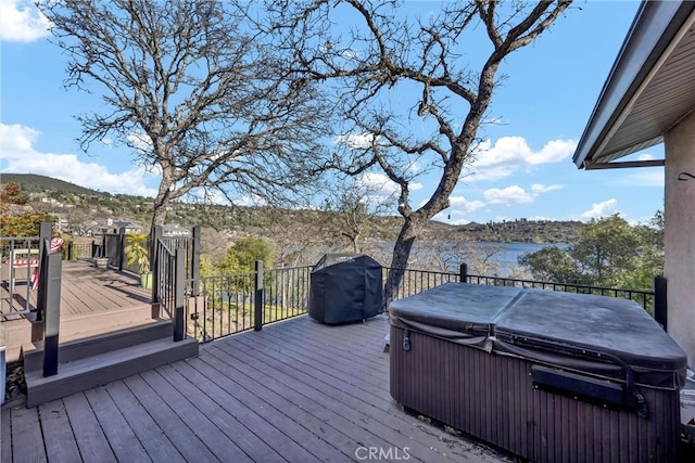 wooden terrace with a water and mountain view, a grill, and a hot tub