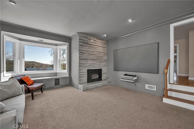 carpeted living room with ornamental molding and a fireplace