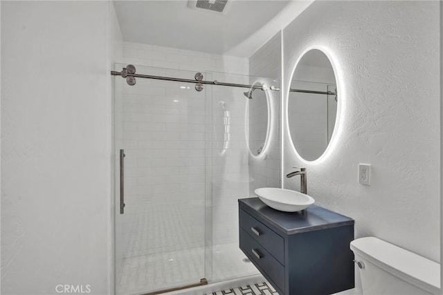 bathroom with toilet, vanity, and an enclosed shower