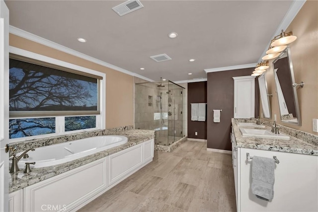 bathroom featuring vanity, ornamental molding, and separate shower and tub