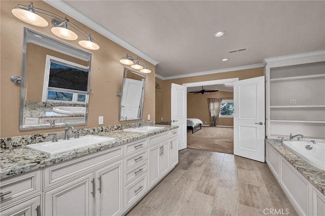 bathroom with ceiling fan, a bath, hardwood / wood-style floors, vanity, and ornamental molding