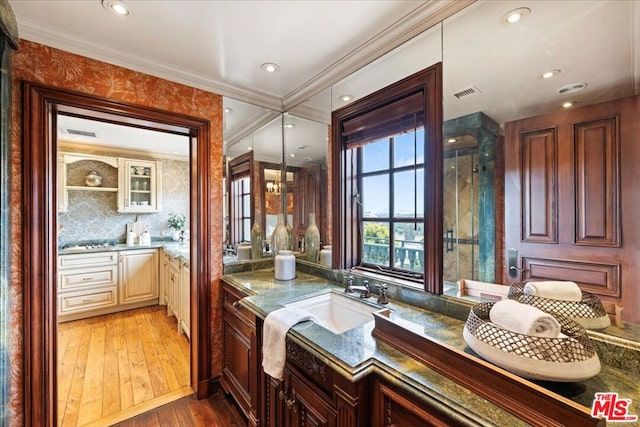 bathroom featuring vanity, decorative backsplash, crown molding, and hardwood / wood-style flooring