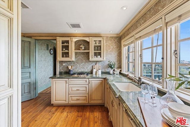 kitchen featuring dark stone countertops, light hardwood / wood-style floors, sink, plenty of natural light, and ornamental molding