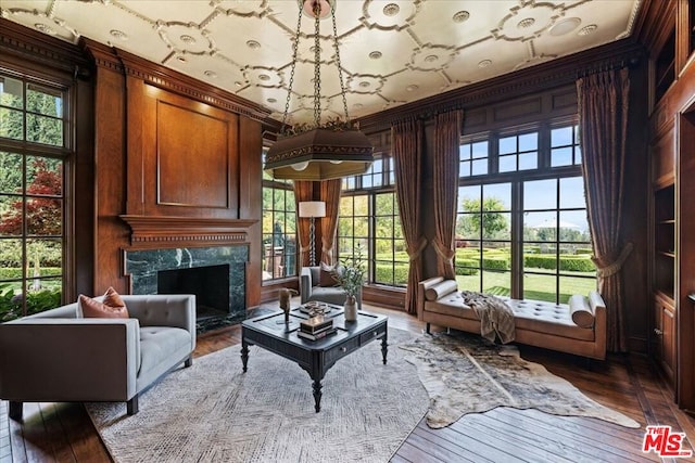 sitting room featuring crown molding, a fireplace, hardwood / wood-style floors, and wooden walls