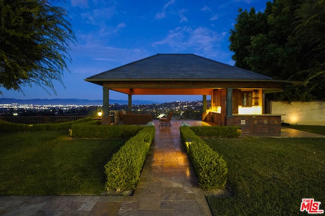 patio terrace at dusk featuring a lawn and a gazebo