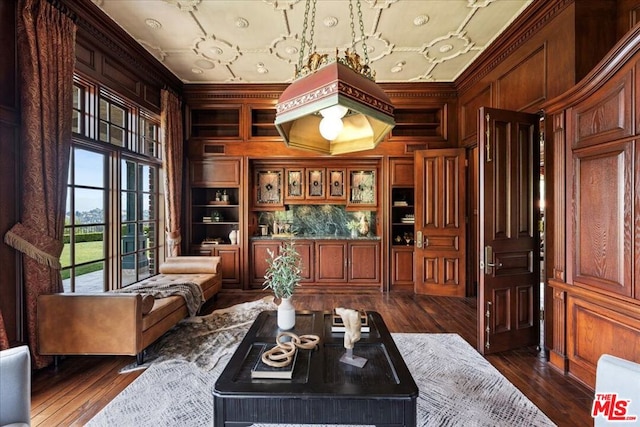 living area featuring dark hardwood / wood-style floors, wood walls, and ornamental molding