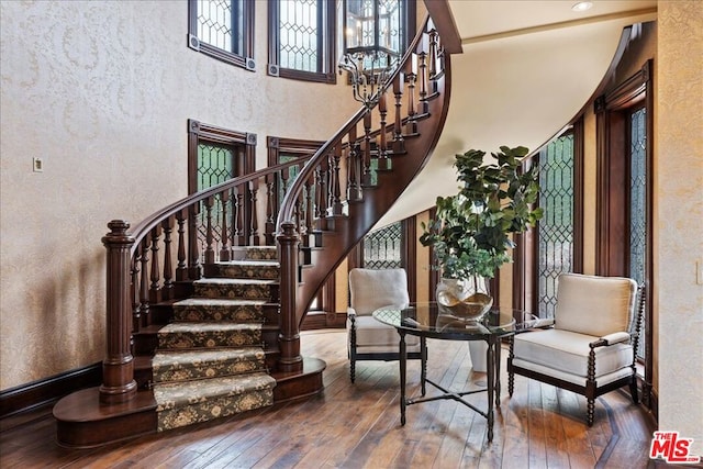 stairway with a towering ceiling and hardwood / wood-style floors