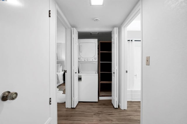 corridor featuring stacked washer and clothes dryer and wood-type flooring