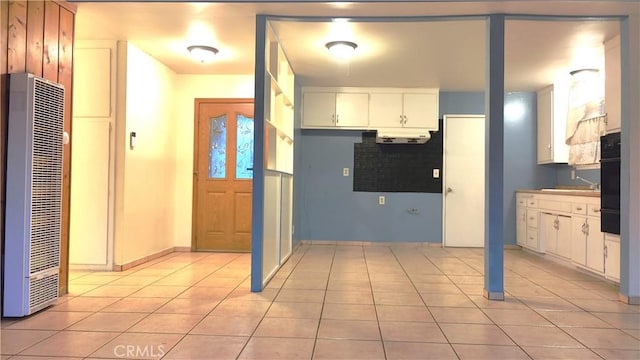 kitchen with light tile patterned floors, black oven, and white cabinets