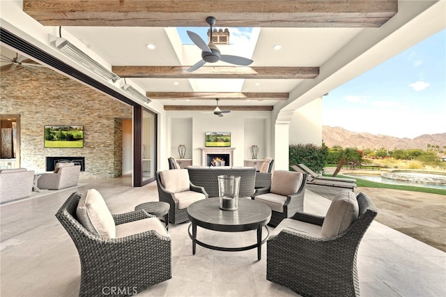 view of patio / terrace with ceiling fan and an outdoor living space with a fireplace