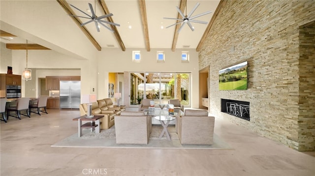 living room with beam ceiling, a stone fireplace, ceiling fan, and a high ceiling