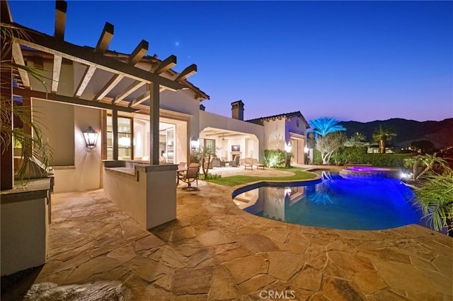 pool at dusk with a patio and exterior bar