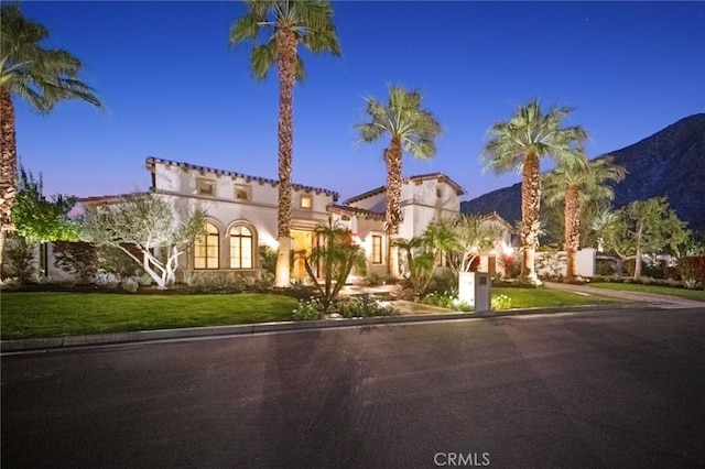 mediterranean / spanish-style house with a mountain view and a lawn