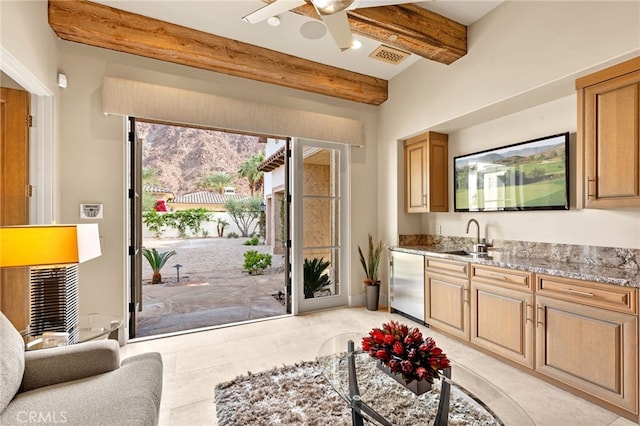 kitchen with dishwashing machine, sink, ceiling fan, beam ceiling, and light stone counters