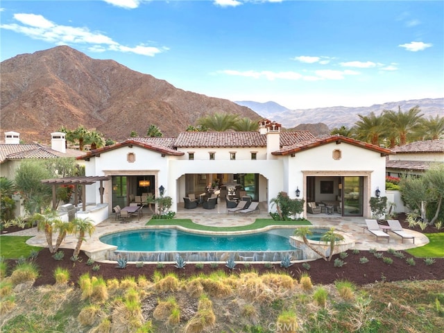 back of house featuring a swimming pool with hot tub, a pergola, a mountain view, and a patio area