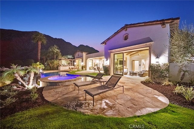 exterior space with a patio, a mountain view, and an in ground hot tub