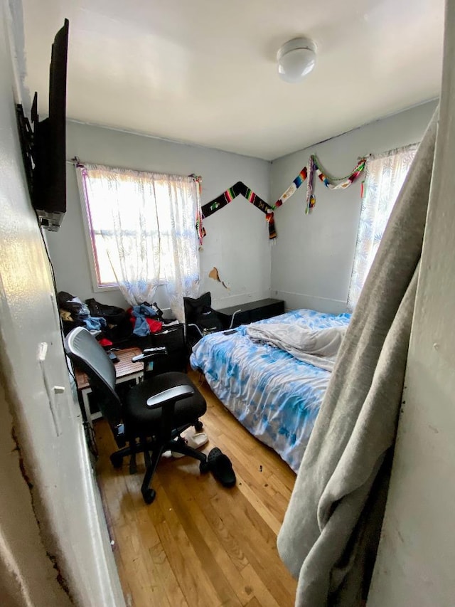 bedroom with hardwood / wood-style flooring and multiple windows