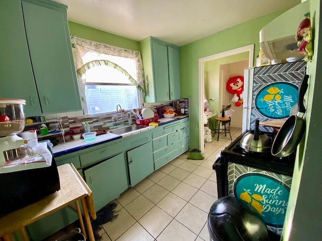 kitchen with sink, tasteful backsplash, ventilation hood, green cabinetry, and tile counters