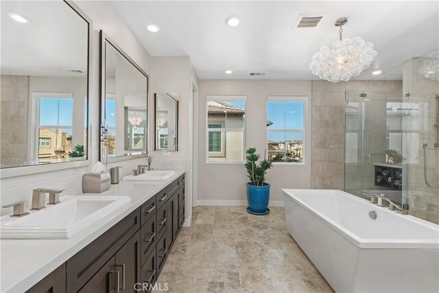 bathroom with an inviting chandelier, vanity, and separate shower and tub