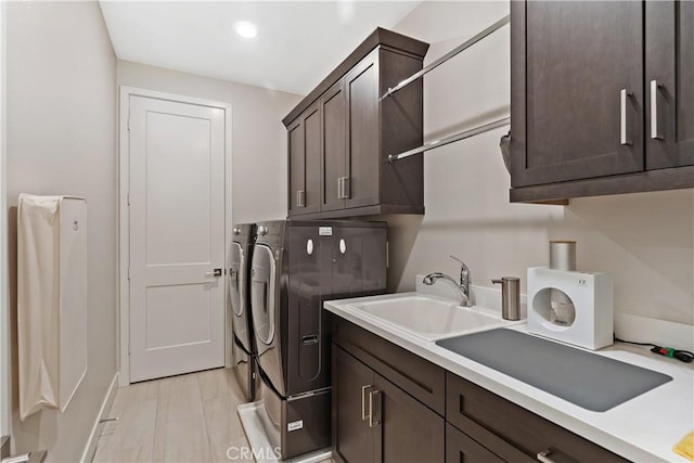 laundry room featuring a sink, cabinet space, washing machine and dryer, and light wood finished floors