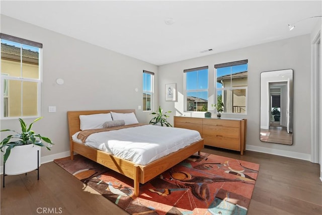 bedroom with visible vents, baseboards, and wood finished floors