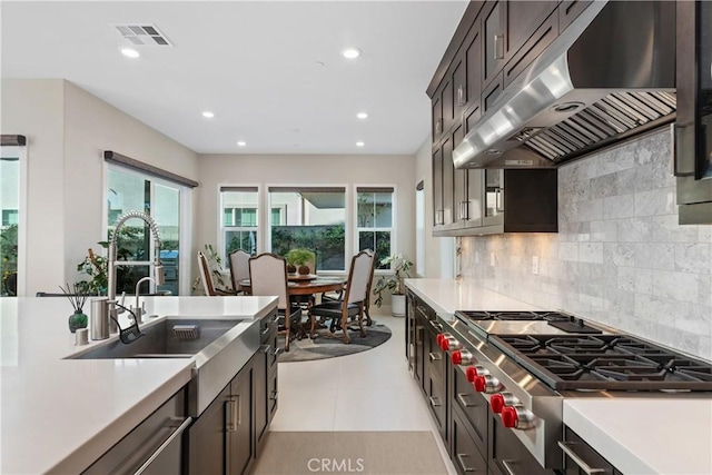 kitchen featuring light tile patterned flooring, stainless steel gas stovetop, decorative backsplash, exhaust hood, and dark brown cabinetry