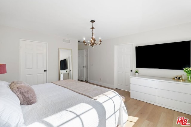 bedroom featuring light wood-type flooring and a chandelier