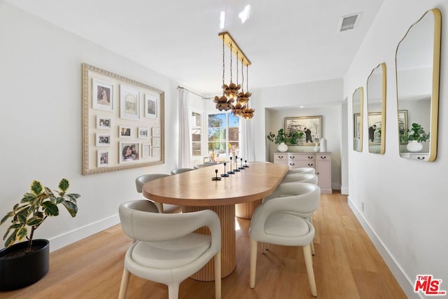 dining space with light hardwood / wood-style floors and a chandelier