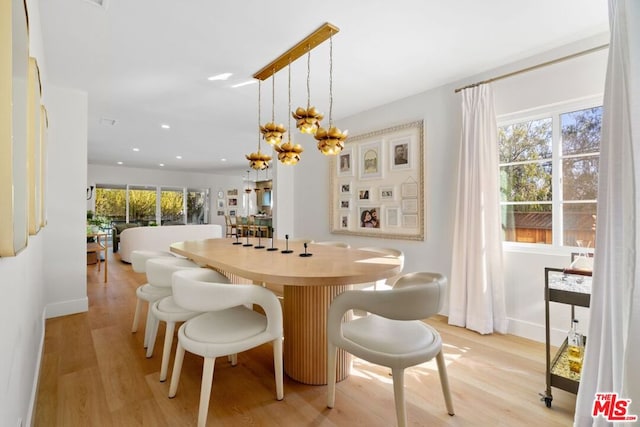 dining room with light hardwood / wood-style flooring and an inviting chandelier