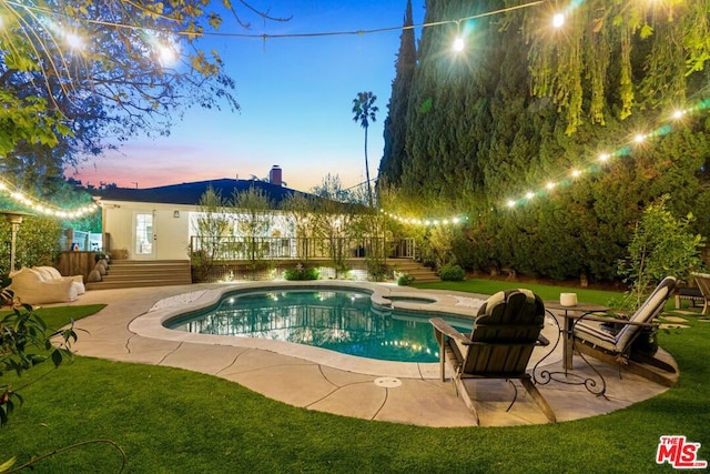 pool at dusk with a lawn, a patio, and an in ground hot tub