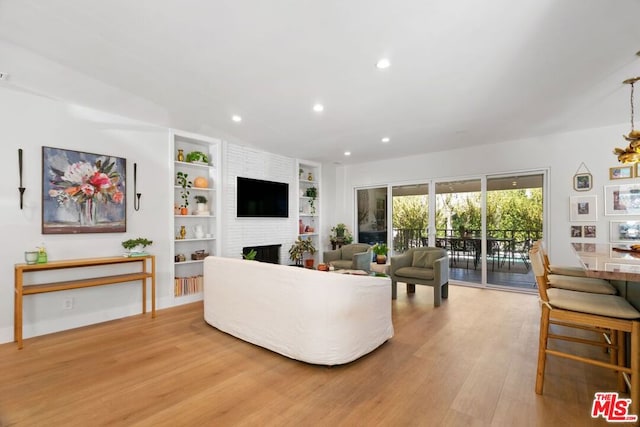 living room with a fireplace, built in features, and light hardwood / wood-style flooring