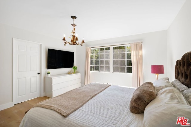 bedroom with light wood-type flooring and a notable chandelier