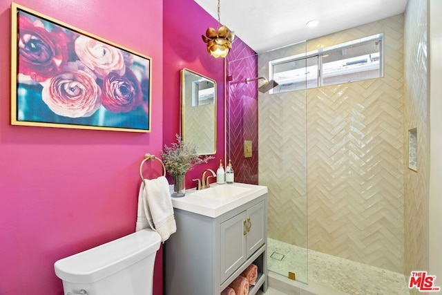 bathroom featuring toilet, a tile shower, and vanity