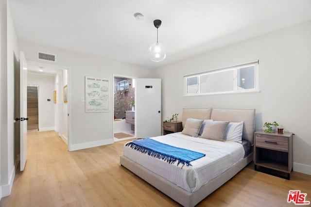 bedroom featuring light wood-type flooring and connected bathroom