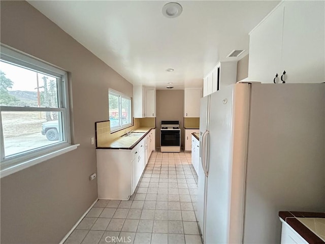 kitchen with sink, light tile patterned floors, white cabinets, and white appliances