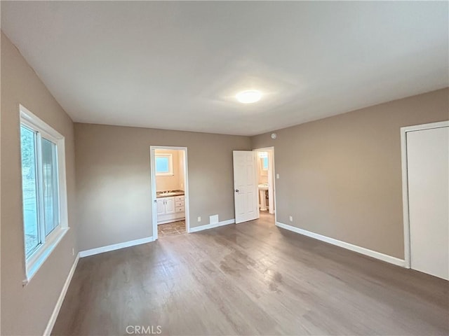 unfurnished bedroom with dark wood-type flooring and connected bathroom