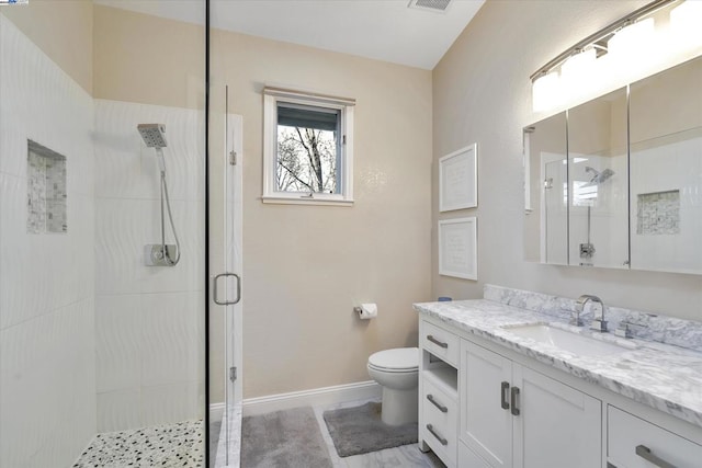 bathroom with toilet, vanity, and an enclosed shower