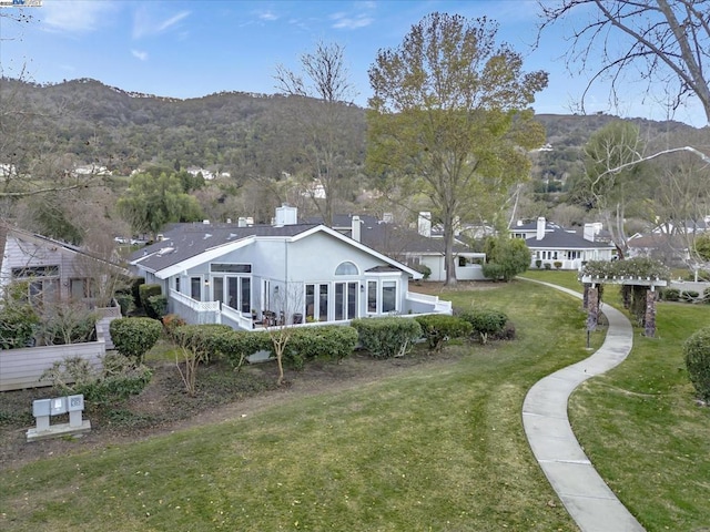 rear view of house with a mountain view and a lawn