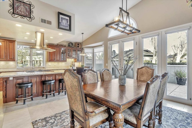 dining area with light tile patterned flooring and high vaulted ceiling