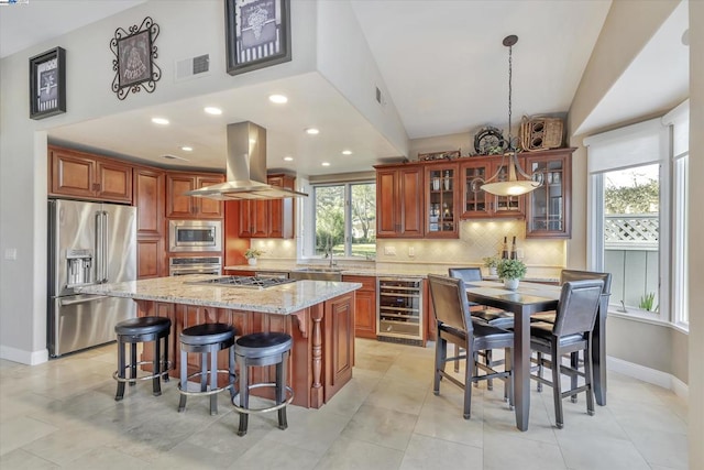 kitchen with wine cooler, light stone countertops, a center island, island range hood, and stainless steel appliances