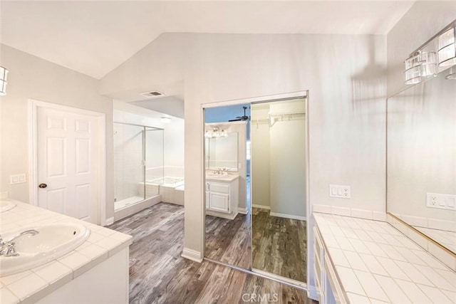 bathroom featuring a shower with shower door, hardwood / wood-style floors, vanity, and vaulted ceiling