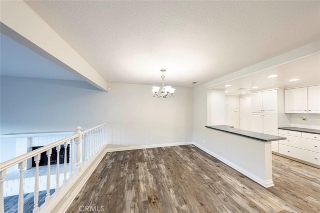 unfurnished dining area with hardwood / wood-style flooring, a textured ceiling, and a chandelier