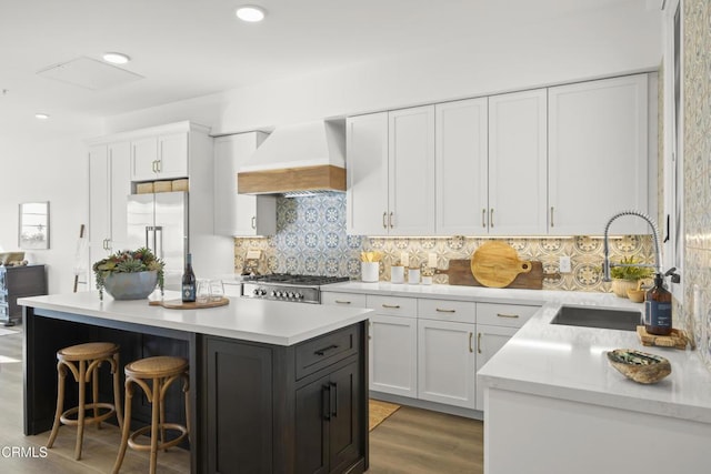 kitchen with white cabinetry, high quality fridge, custom exhaust hood, and sink