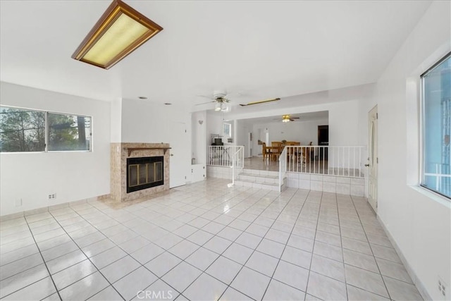 unfurnished living room featuring ceiling fan, light tile patterned floors, and a premium fireplace