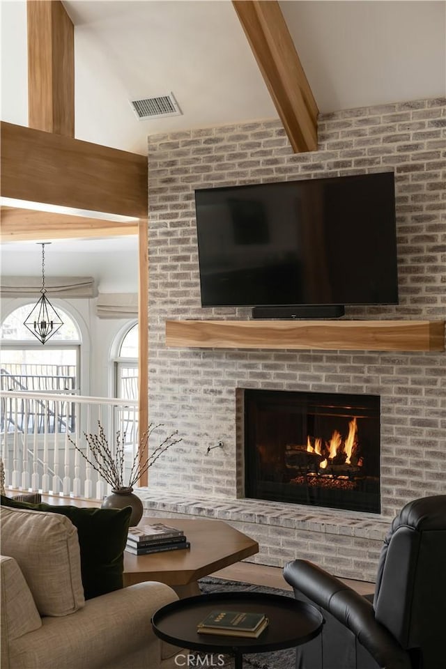 living room featuring a notable chandelier, beamed ceiling, and a fireplace