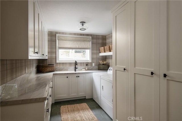 laundry area with dark tile patterned floors, sink, separate washer and dryer, and cabinets