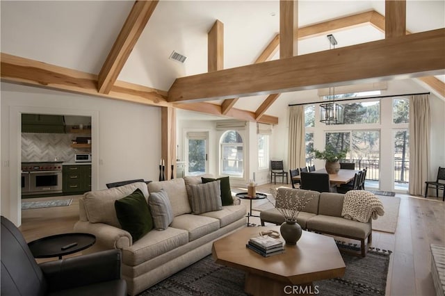 living room with high vaulted ceiling, beamed ceiling, a chandelier, and hardwood / wood-style flooring