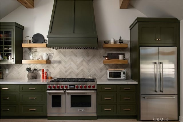 kitchen featuring high end appliances, decorative backsplash, custom exhaust hood, and green cabinetry