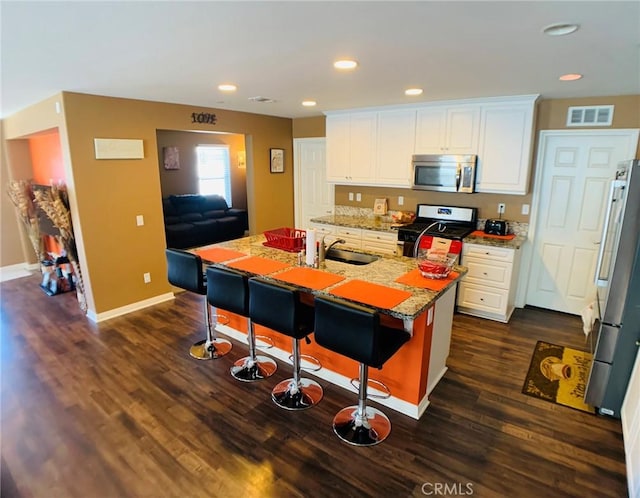 kitchen with sink, white cabinets, dark hardwood / wood-style flooring, stainless steel appliances, and a center island with sink