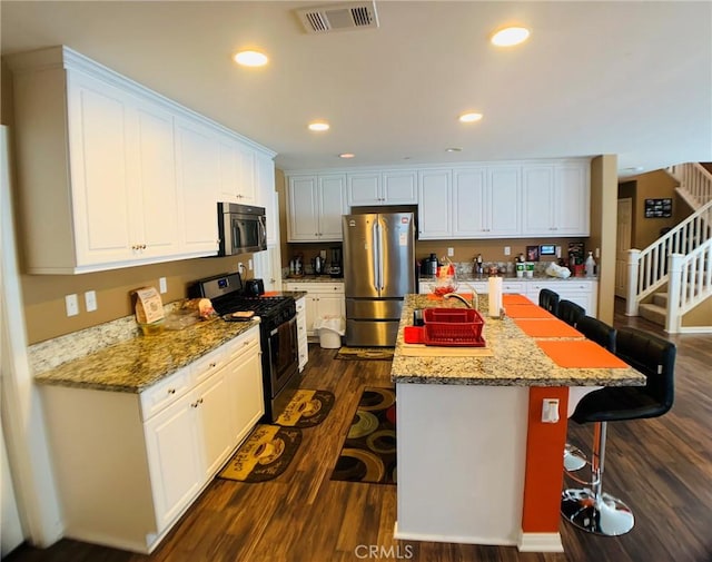 kitchen featuring white cabinetry, appliances with stainless steel finishes, a kitchen breakfast bar, and a kitchen island with sink